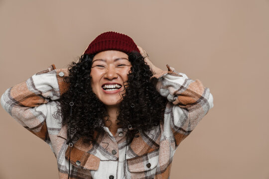 Asian woman grabbing her head isolated over beige background