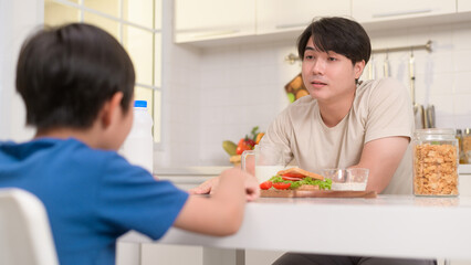Obraz na płótnie Canvas Young Asian father angry his son about eat vegetables in kitchen at home