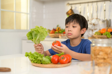  Asian boy feeling bored , unhappy to eat vegetables , health care concept