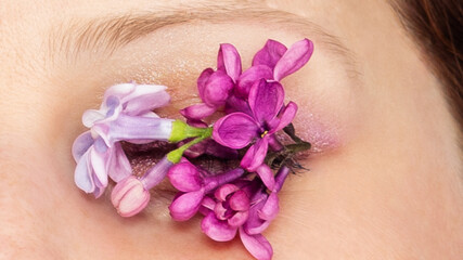 Obraz na płótnie Canvas lilac flowers on girl's eyelashes, make-up 