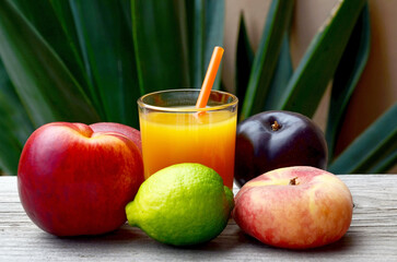 Fresh ripe fruits and a glass of juice in tropical garden background.Multi fruit juice.Juice mix fruit on wooden table.
Healthy drink or diet concept.Selective focus.