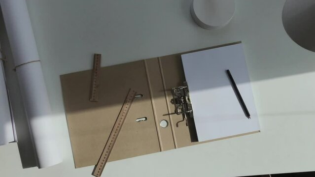 An album of A4 sheets, a pencil and a ruler lie on the architect's white desk.