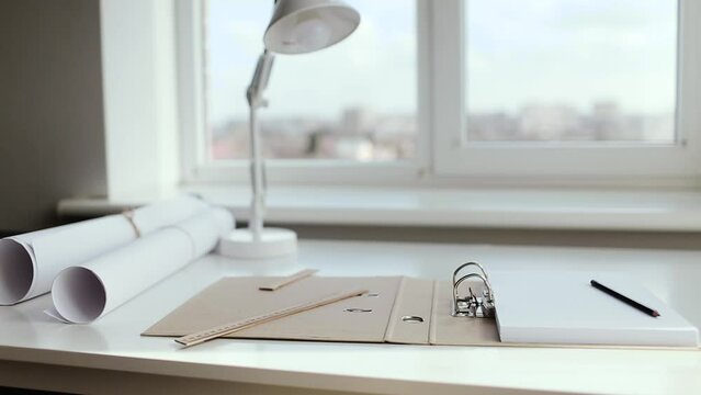 An album of A4 sheets, a pencil and a ruler lie on the architect's white desk.