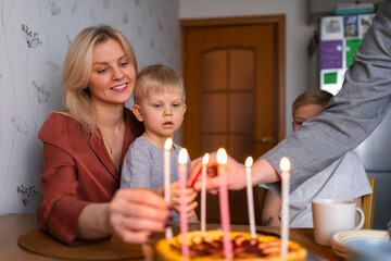 Obraz na płótnie Canvas Family smiling while burning candles on pie during birthday celebration at home
