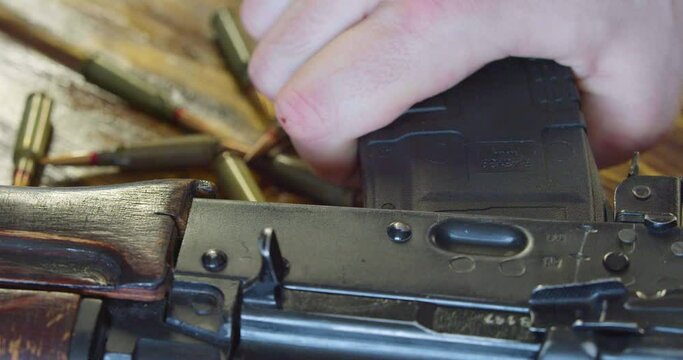 Close-up view of the attachment of the magazine to the Kalashnikov assault rifle in preparation for battle.