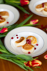 Homemade cottage cheese cheesecakes with sour cream and red currant berries with red tulips