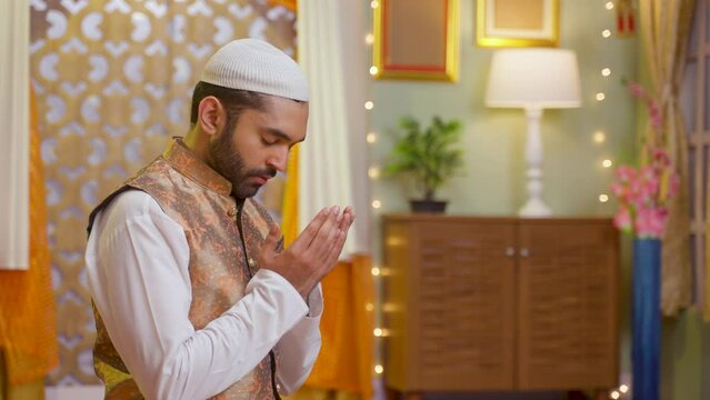 side view shot of young indian muslim man doing holy namaz at home during ramdan festival - concept tredition,culture and festive celebration.