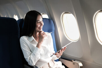 Asian businesswoman writing report sitting thinking looking out the window