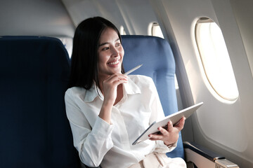 Asian businesswoman writing report sitting thinking looking out the window