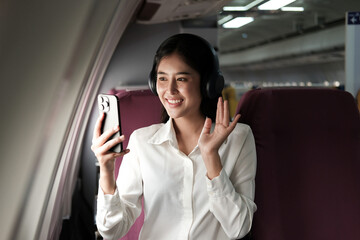 Fun Asian woman sits on plane and uses smartphone. Video accompaniment while traveling.