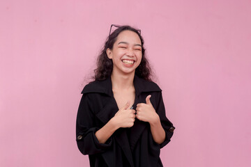 A cheerful woman laughing while making a double thumb up sign. Isolated on a pink background.