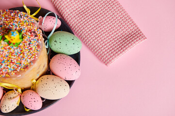Cropped view of Easter orthodox sweet bread and colorful eggs on light pink pastel background. Easter holidays breakfast concept. Copy advertising space. Panettone Russian kulich Easter cake. Top view