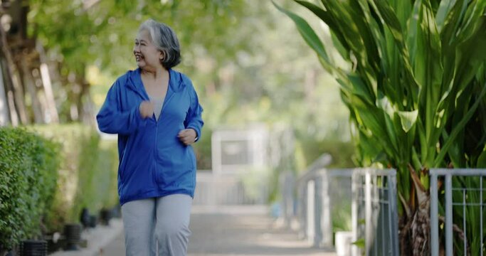 Asian senior woman warming up and jogging in the park. Health care for the elderly. Exercise activities to keep your body healthy. Concept Workout