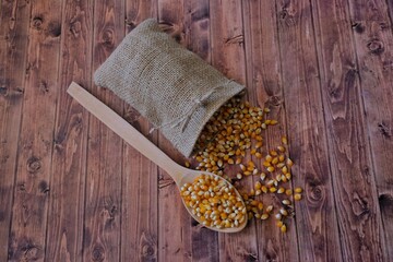 Fototapeta na wymiar Corn in a wooden spoon. Corns in a cloth bag.