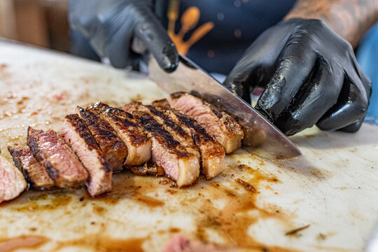 Assador cortando carne assada na grelha na brasa da parrilla