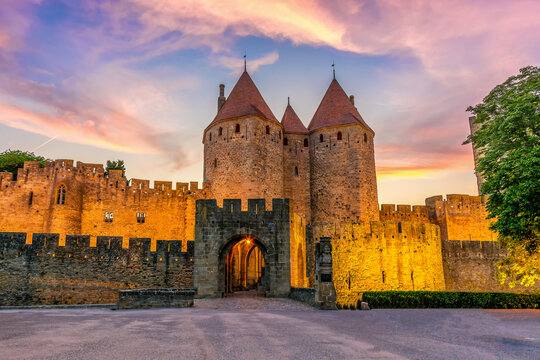 Night view of Carcassone medieval city in France against dramatic sunset sky
 