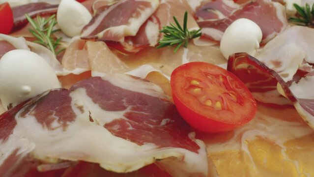 Slices of raw ham with fresh rosemary, mozzarella and tomatoes