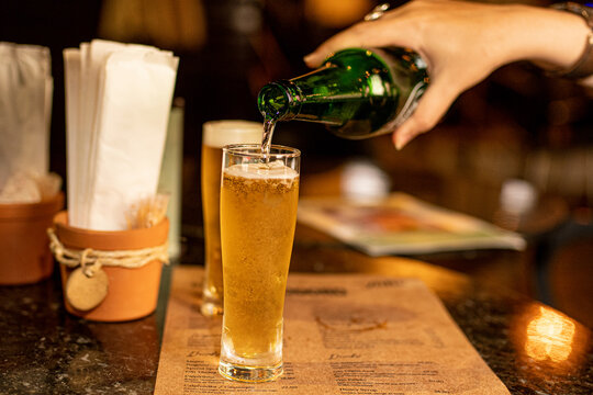 Pessoa colocando cerveja no copo no bar na mesa de boteco