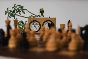 Wooden chess pieces and timer clock behind them