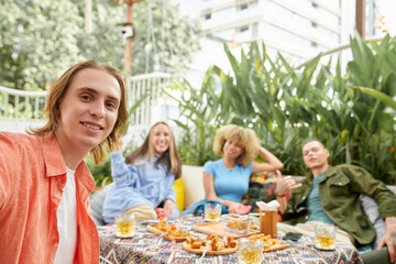 Happy young man filming video with friends for social media