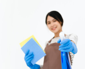 Happy young woman wearing blue rubber gloves for hands protection , holding sponge and spray bottle , smiling at camera while cleaning house isolated over white background