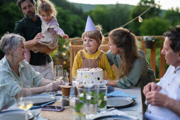 Multi generation family celebrating birthday and have garden party outside in the backyard on patio.