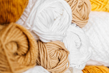 White shelving with colored balls of yarn for knitting. Bright yarn balls lined up on the shelves. Organizing and storage in craft room. Handmade, needle craft, creativity and  hobby.