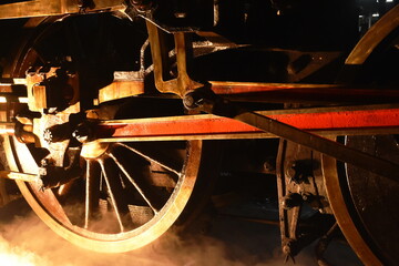 steam locomotive iron wheel with smoke floating on railway in night