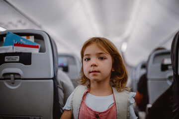 Happy little girl standing in aisle in the plane.