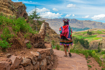 Peruvian indigenous quechua woman in traditional clothing walking along Inca Trail, Sacred Valley, Cusco, Peru. - obrazy, fototapety, plakaty