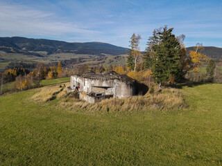 Fototapeta na wymiar Autumn meadows with an old czechoslovak bunker and Kralicky Sneznik in the background, Czechia.