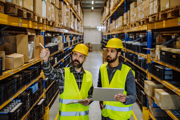 Warehouse workers checking stuff in warehouse with digital system in tablet.