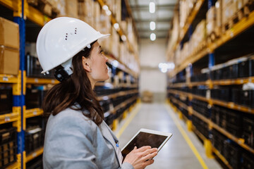 Manager woman in suit controlling goods in a waehouse.