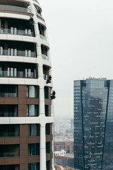 Window cleaners do their job washing windows in a high-rise building at a height