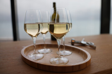 Lot of glasses with white wine and bottle standing on table in restaurant closeup