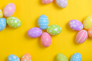 Happy easter holiday celebration concept. Group of painted colourful eggs decoration on a yellow background. Seasonal religion tradition design. Top view, flat lay, copy space.