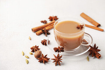 Masala tea or karak chai in a glass cup with cardamom, star anise and cinnamon. - obrazy, fototapety, plakaty
