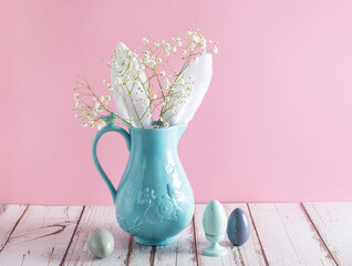Blue ceramic jar with rabbit ears and bouquet of white small flowers of Gypsophila paniculata on...