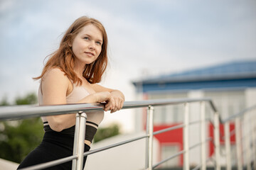 the girl stands on the stairs and leans on the railing