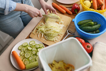 Woman cooking lunch and composting organic food waste in a bokashi container. Female person...