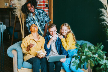 diversity and international group of young people students watching movie on laptop having fun together eating popcorn in college dorm