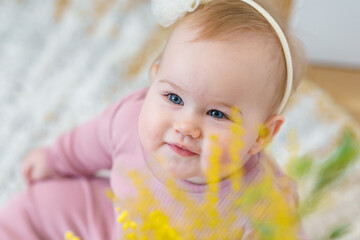 Cute Caucasian girl baby toddler and a bouquet of yellow mimosa flowers, spring concept