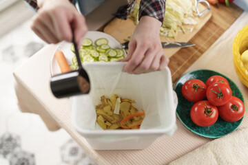 Woman composting food waste at home. Female making a compost with organic food scraps in a bokashi bin. Person put bran into composter