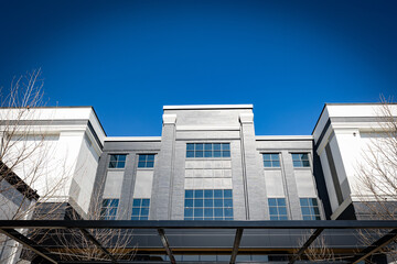 On a bright winter day, the sun illuminates a gray and white industrial building front that features a canopy.