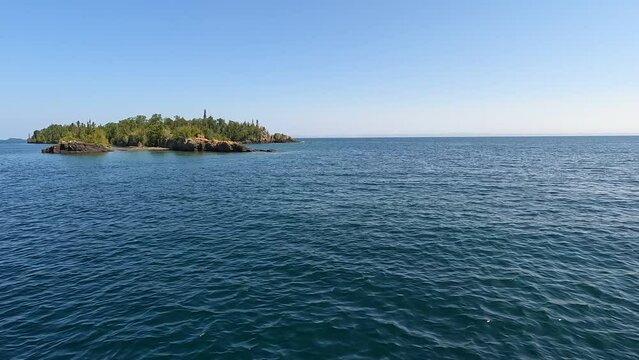 Riding on a ferry boat, leaving the coast of Rock Harbor at Isle Royale National Park. Looking over the vast expanse and pure blue waters of Lake Superior. Slow motion.