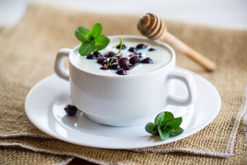 Cooked milk semolina porridge with berries and honey in a plate.