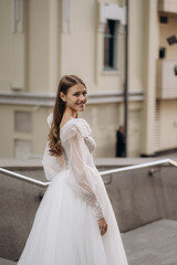 Portrait of beautiful bride in a white gorgeous wedding dress. Fashionable wedding dress with cleavage, wide long sleeves decorated with lace and beads