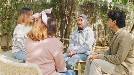 Small Asian group of people sit in a close circle and talk to a therapist in park. Smile people...