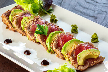 Seared tuna dish served with slices of avocado