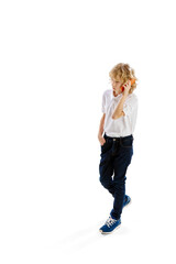 Isometric view. Little boy, child with blonde hair in shirt walkign and talking on mobile phone against white background. Concept of childhood, emotions, facial expression. Ad